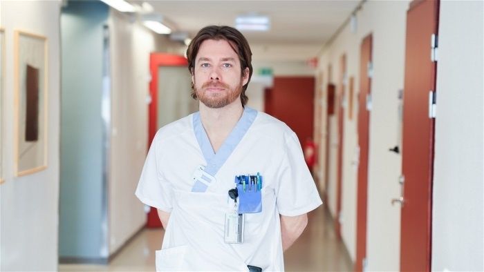 Vårdpersonal i vit arbetsdräkt står i en sjukhuskorridor
