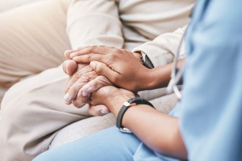 Vårdpersonal håller en patients händer under ett samtal